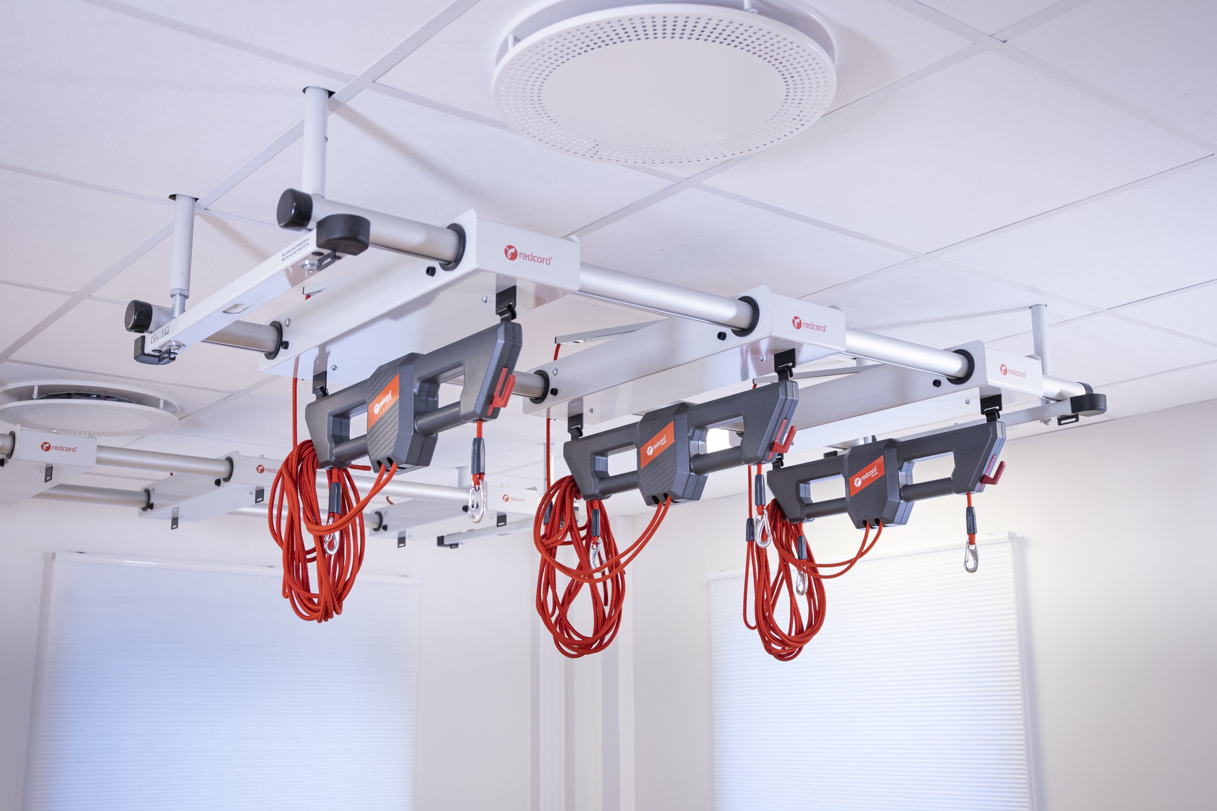 A row of ceiling-mounted Redcord Workstations installed in a bright clinic